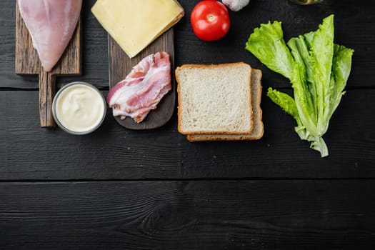 Ingredients for sandwich, bacon, cheese, tomato, chicken meat, lettuce, sauce, on black wooden background, top view with copy space for text