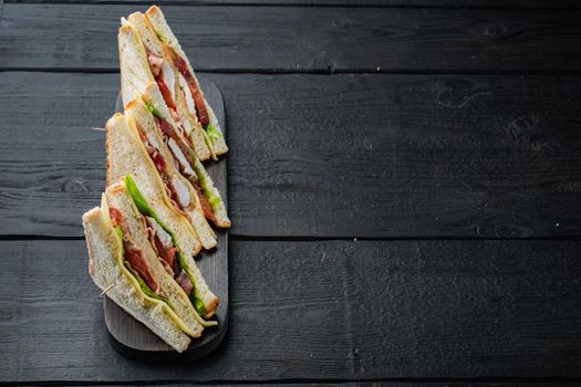 Homemade chicken sandwich halves, on black wooden table with copy space for text