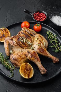 Roasted spatchcock poussin meal, on black background
