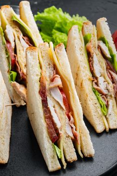 Sandwich bread tomato lettuce and yellow cheese, on black background