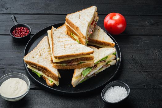 Sandwich bread tomato lettuce and yellow cheese, on black wooden background