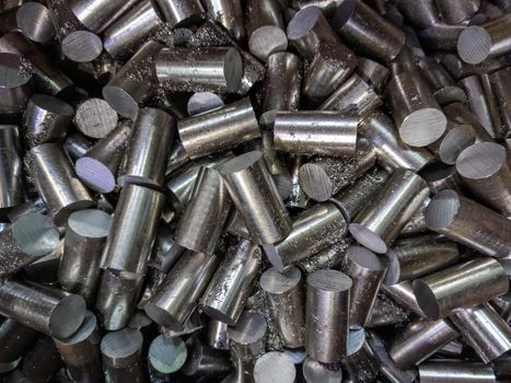 a pile of sawed stainless steel rod chunks - full frame close-up industrial background.