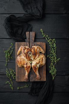 Roasted whole poussins, on black wooden background, top view
