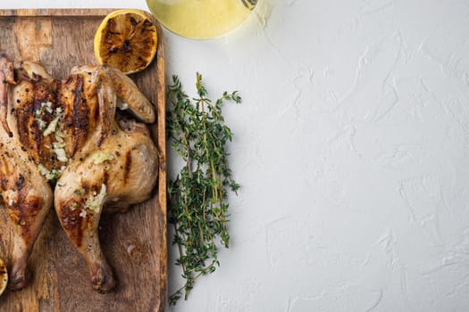 Roasted whole poussins, on white background, top view with copy space for text