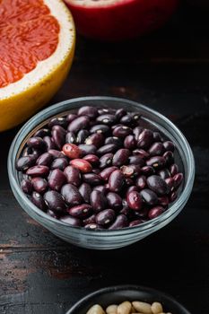 Red beans in bowl with healthy ingredients on dark wooden background.