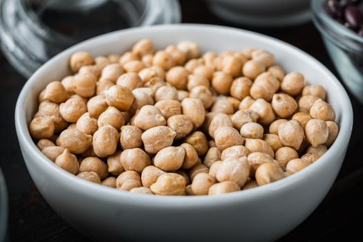 Chickpea in white bowl on dark wooden background.
