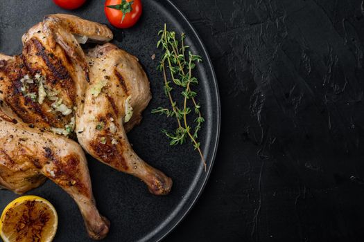 Spatchcocked chicken and herbs, on black background, top view with copy space for text