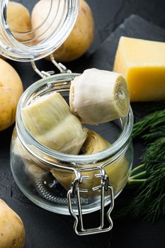 Pickled artichokes with oil, on black textured background
