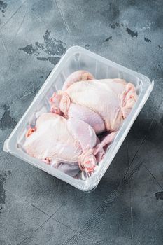 Raw chicken in plastic sealed plastic box, on gray background