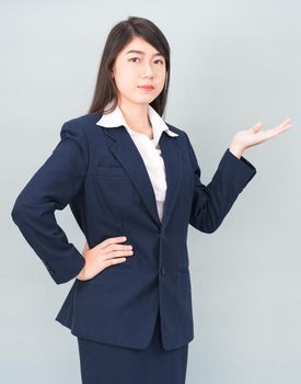 Asian woman in suit open hand palm gestures with empty space isolated on gray background