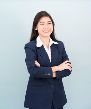 Teenage girl long hair is standing with her arms crossed wearing suit and white shirt on blue background