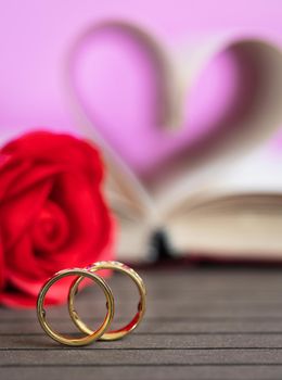 Wedding ring pages of book curved into a heart shape and red rose,Love concept of heart shape from book pages