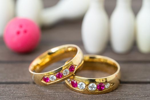 Close up shot wedding rings with bowling pin background