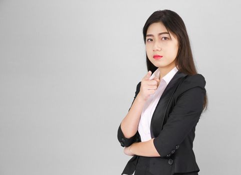 Asian woman in suit looking at camera and pointing finger on gray background