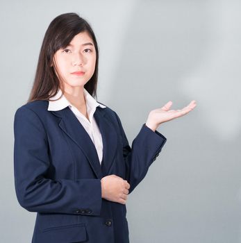 Asian woman in suit open hand palm gestures with empty space on gray background