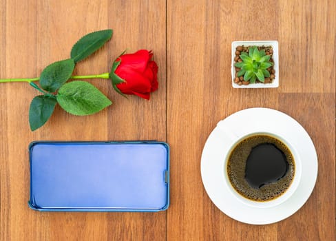 Top view white cup of coffee and red rose with cellphone on wood background valentine concept