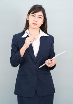 Asian woman in suit using computer digital tablet isolated on gray background