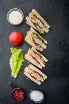 Halves of fresh club sandwiches, on black background, top view