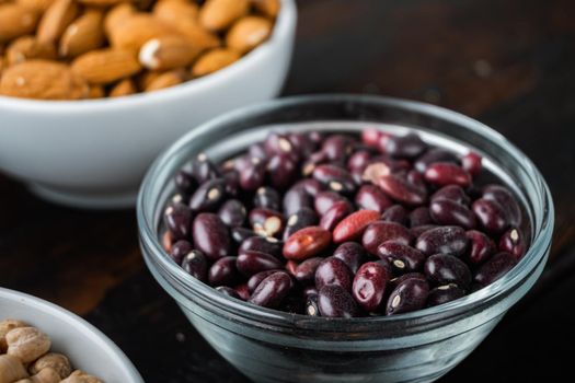 Red beans in bowl with healthy ingredients on dark wooden background.