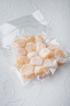 Frozen meat scallops in vacuum package, on white textured background