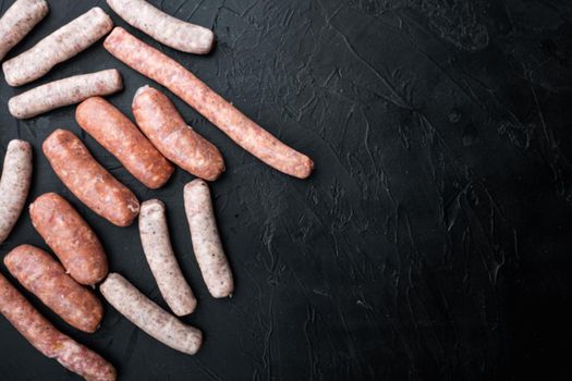 Raw homemade sausages, flat lay with space for text, on black background.
