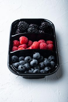 Ripe berries in tray from market, blueberries, raspberry with blackberry, on white background