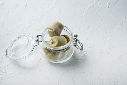 Artichoke hearts marinated with olive oil, on white textured background with space for text