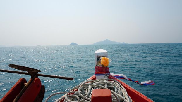 Travel by sea in Thailand by ship. View of the open ocean, green Islands and gray sky in smog. Green water with waves. Sailing between the Islands. Ship from different sides: stern, bow, rope, anchor.