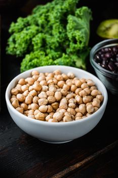 Chickpea in white bowl on dark wooden background.