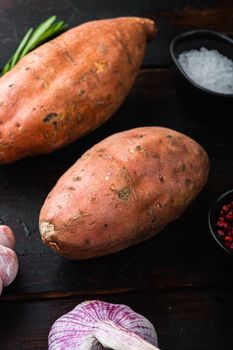 Sweet potato or batat with herbs on old wooden table.
