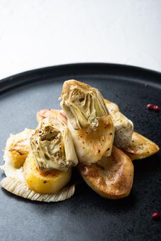 Baked potato, artichoke with fennel al forno, on white textured background