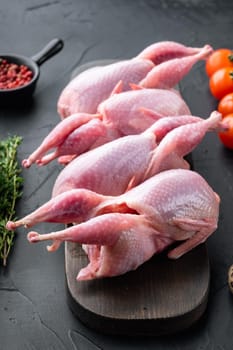 Fresh raw meat quails with herb, on black textured background