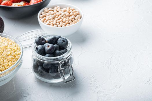 Ripe blueberry in glass jar with space for text, on white background.