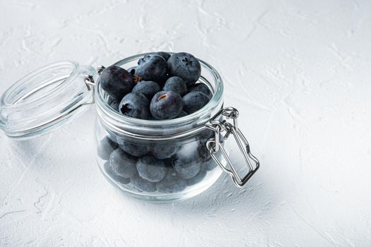 Ripe blueberry in glass jar, on white background.