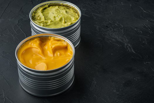 Canned cheese and guacamole sauce in can, on black background with copy space for text