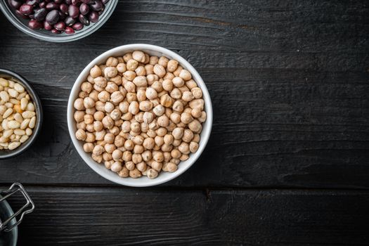 Chickpea in white bowl, top view with space for text, on black wooden background.