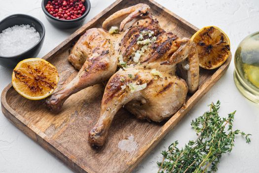 Grilled fried roast chicken tabaka with herbs, on white background