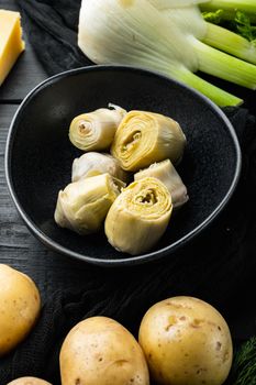 Artichoke hearts marinated with olive oil, on black wooden table
