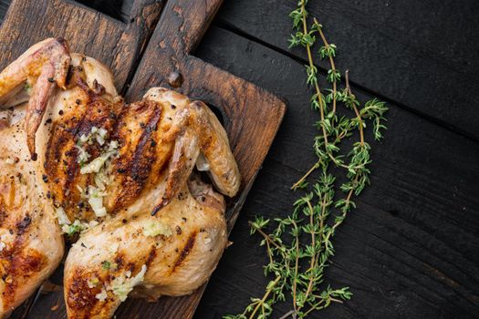 Grilled whole chicken with chimichurri sauce, on black wooden background, top view