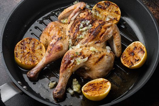Grilled fried roast chicken tabaka with herbs, on old rustic background