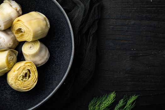 Pickled artichokes with oil, on black wooden table, top view with space for text