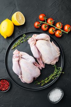 Raw small young whole chicken with herbs spices, on black background, top view