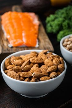 Almonds nuts in bowl on dark wooden background.