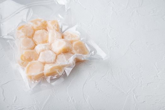 Scallops, in vacuum pack, on white textured background with copy space