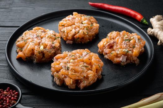 Raw fish patties with salmon fillet and lemongrass, on black wooden table