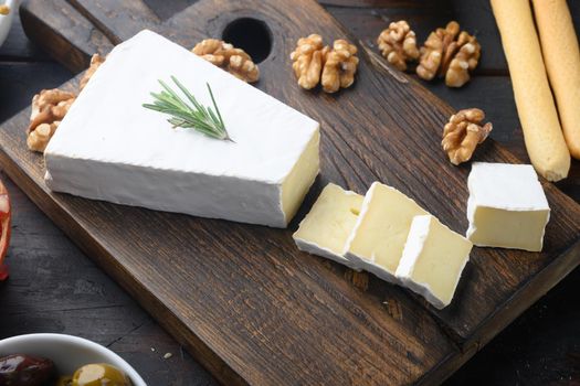 Piece of the brie cheese set, on dark wooden background