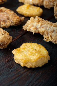 Crispy kentucky fried chicken cuts on dark wooden background.