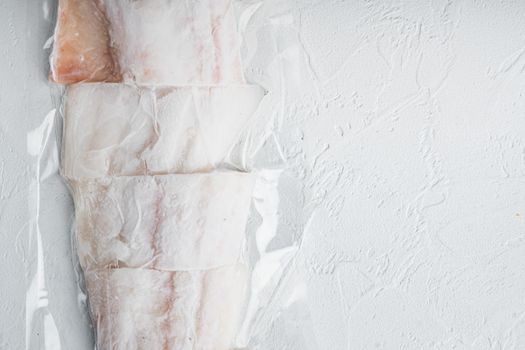 Haddock white fish fillet in plastic market package, on white background, top view with copy space for text