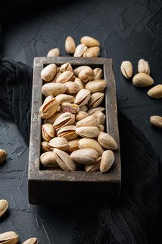 Shelled, unsalted pistachios, on black textured background