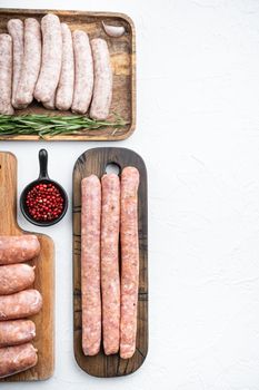 Fresh raw pork, beef and chicken sausages, top view with space for text, on white background.